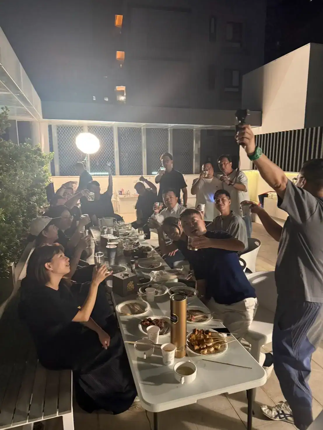 台中燒烤包場實拍｜萬聚所漫遊館頂樓陽台，十幾人圍著同一張長桌吃烤肉、舉杯