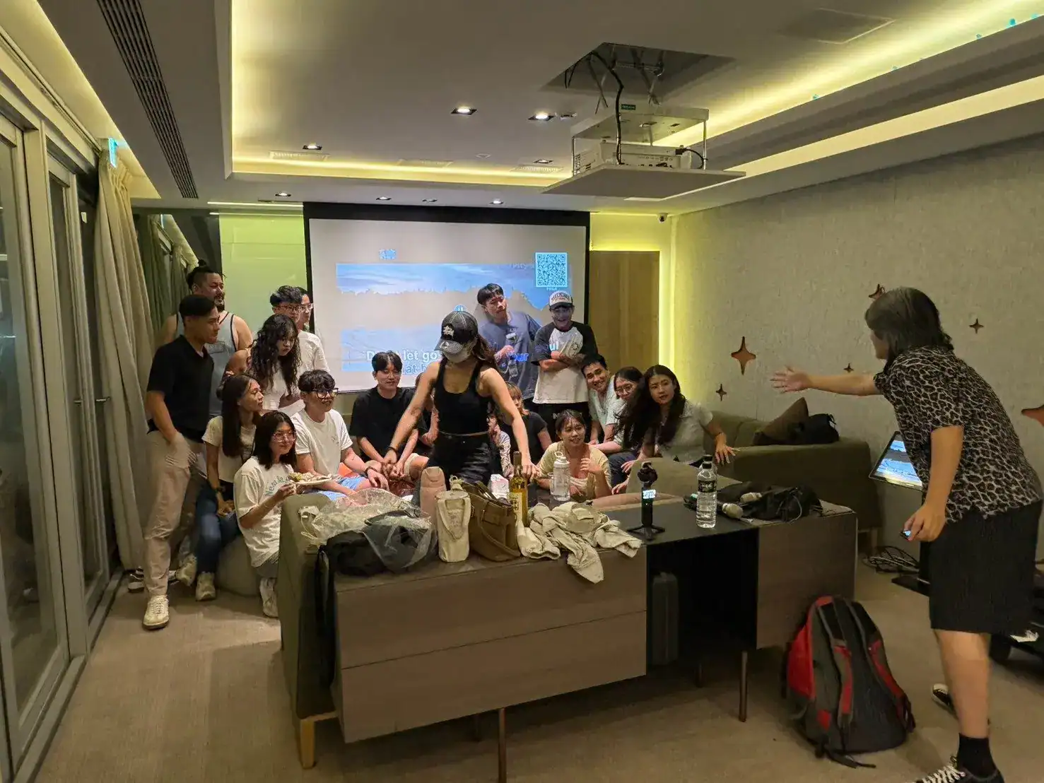 台中燒烤包場｜萬聚所漫遊館室內區，天花板投影機與投影幕播放 KTV，大家圍在螢幕前同樂