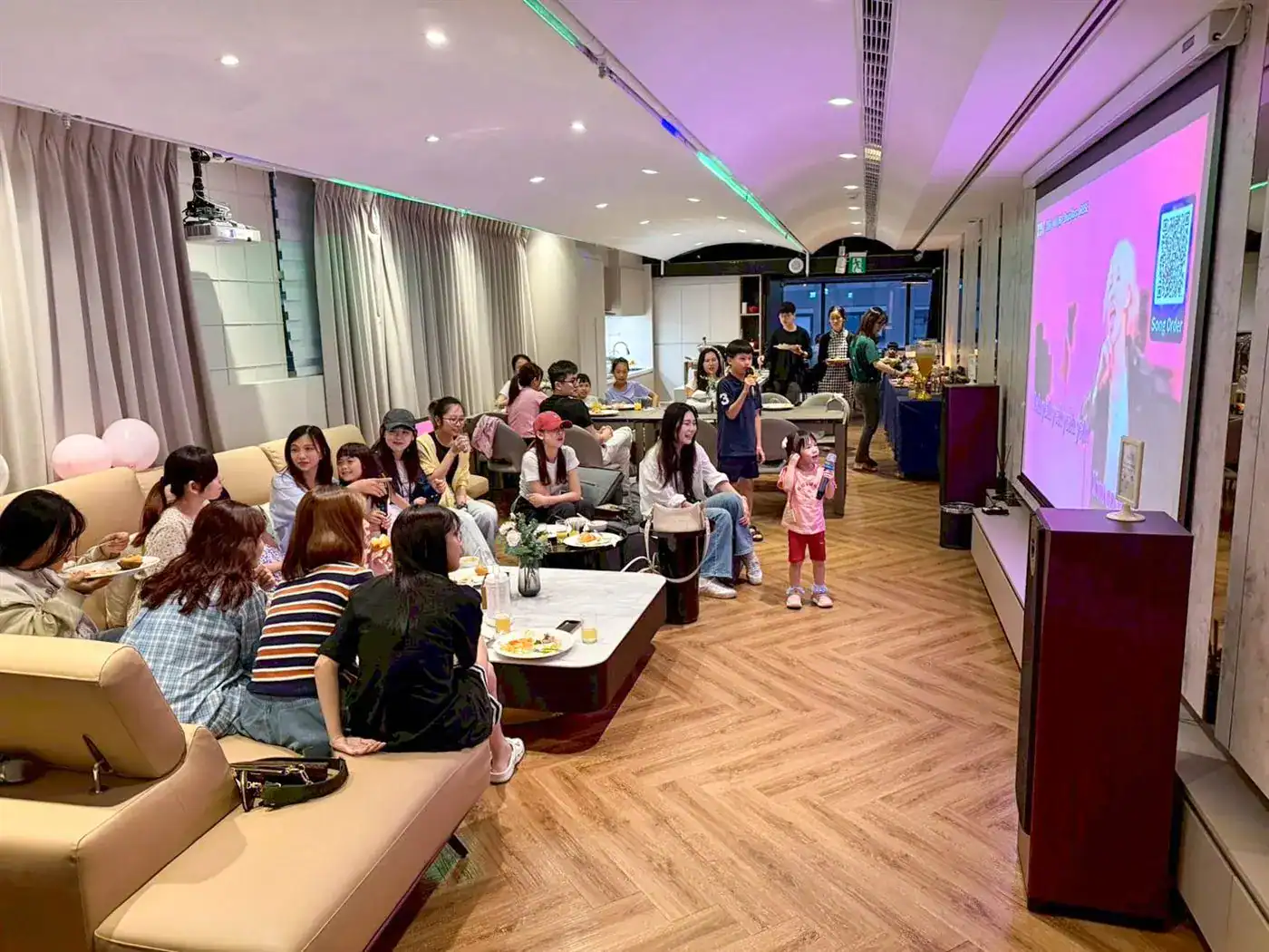 台中家庭聚餐包廂 萬聚所勤美館實拍：投影幕上有點歌 QR code，小孩拿麥克風唱歌，大人坐沙發觀看