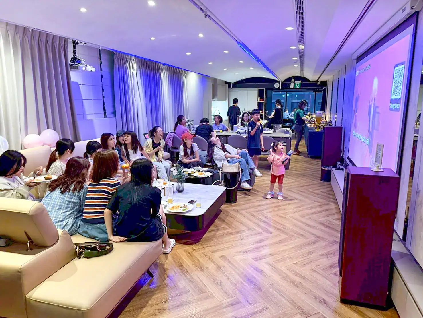 萬聚所勤美館 A 區，沙發區邊吃邊看小孩拿麥克風唱歌，最裡面是取餐檯