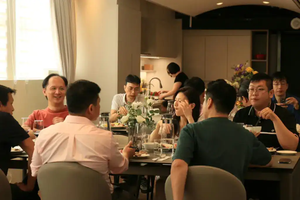 萬聚所包場空間聚餐，大家圍著長桌吃飯聊天，後方是廚房
